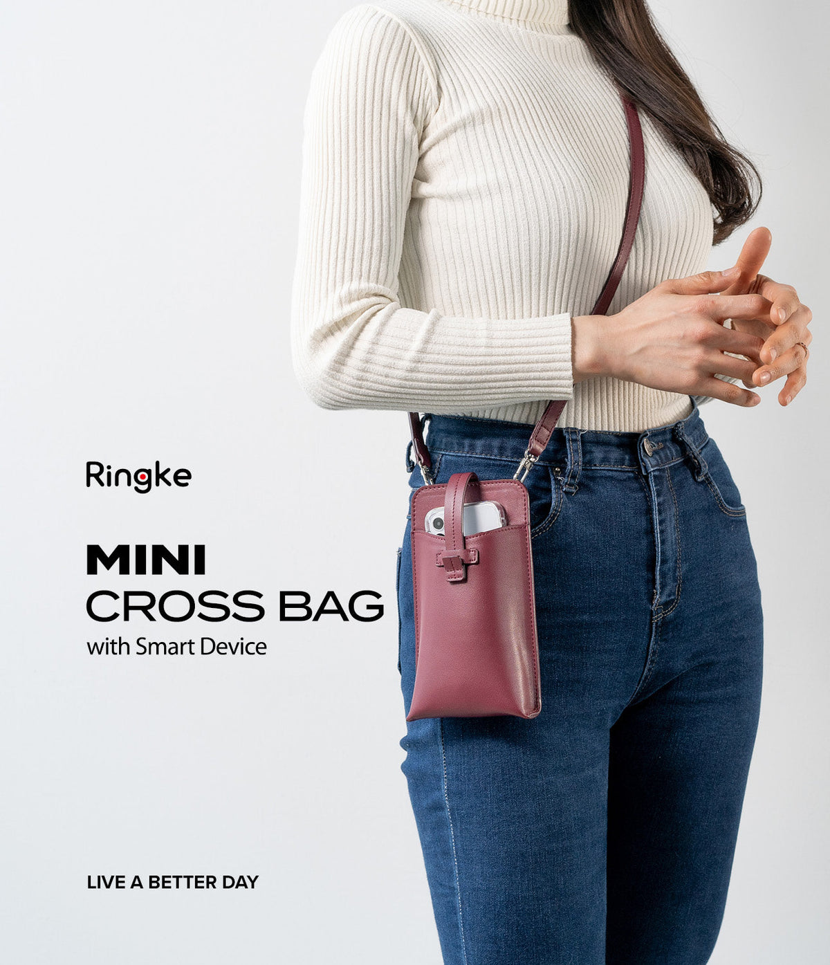 Mini Cross Bag | PU Leather - Mini Cross Bag - A person wearing a maroon PU leather mini crossbody bag containing a smartphone over a white top and jeans.