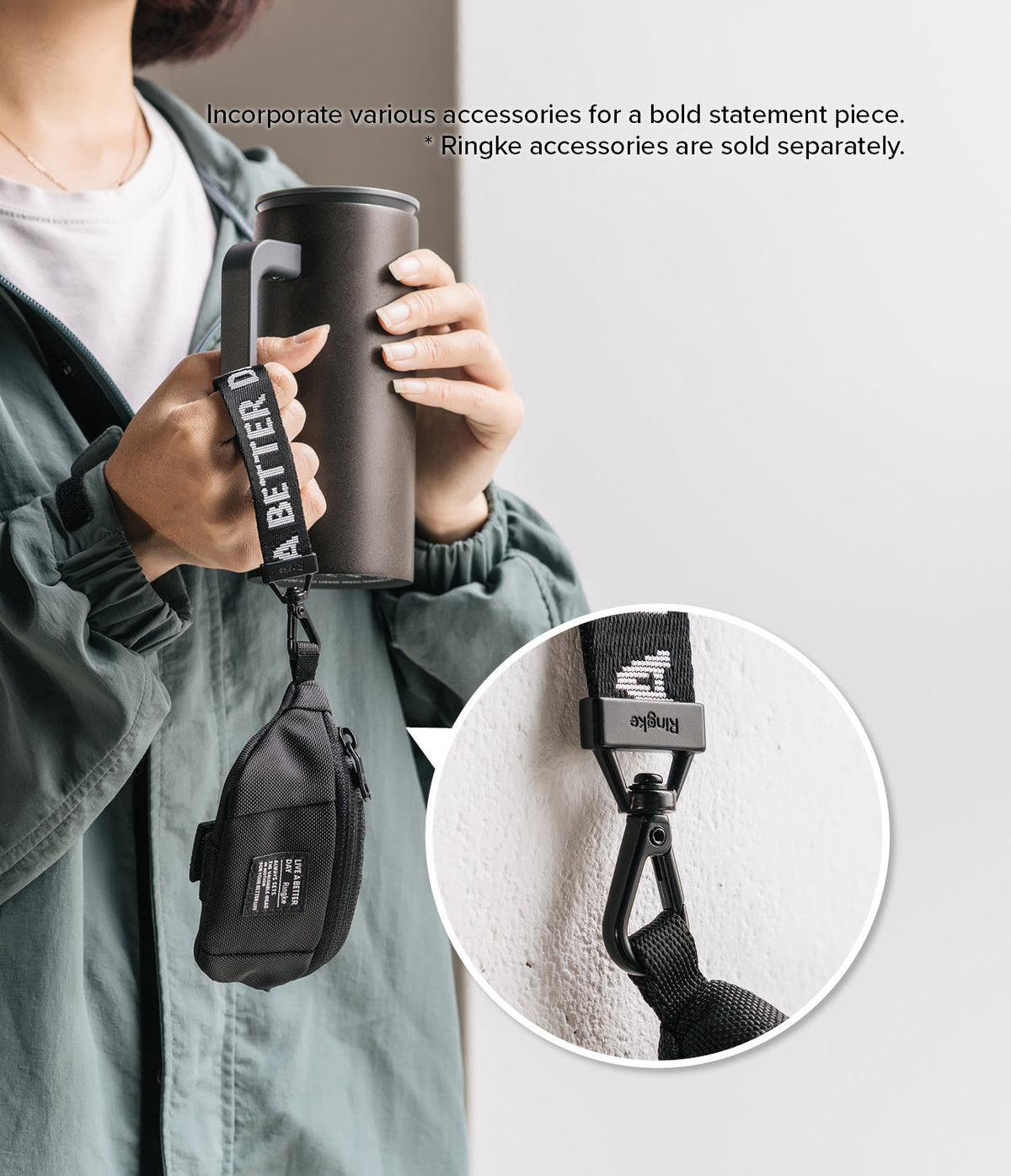 Mini Pouch | Sling Bag - A person holds a tumbler with a branded black strap attached to a small black pouch via a carabiner.