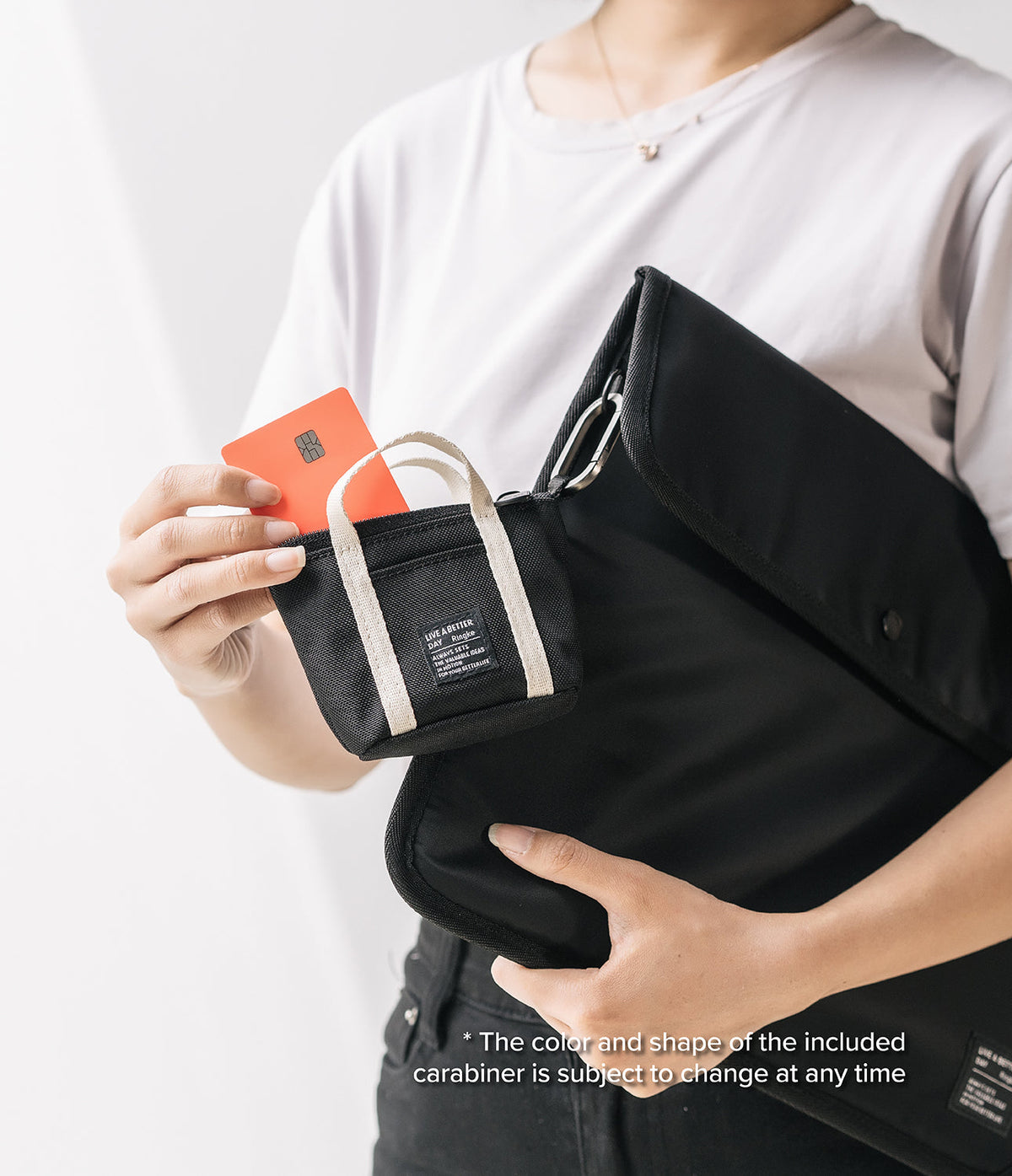 Mini Pouch | Tote Bag - A person holding a black mini tote pouch with a credit card inside, clipped to a larger black bag.