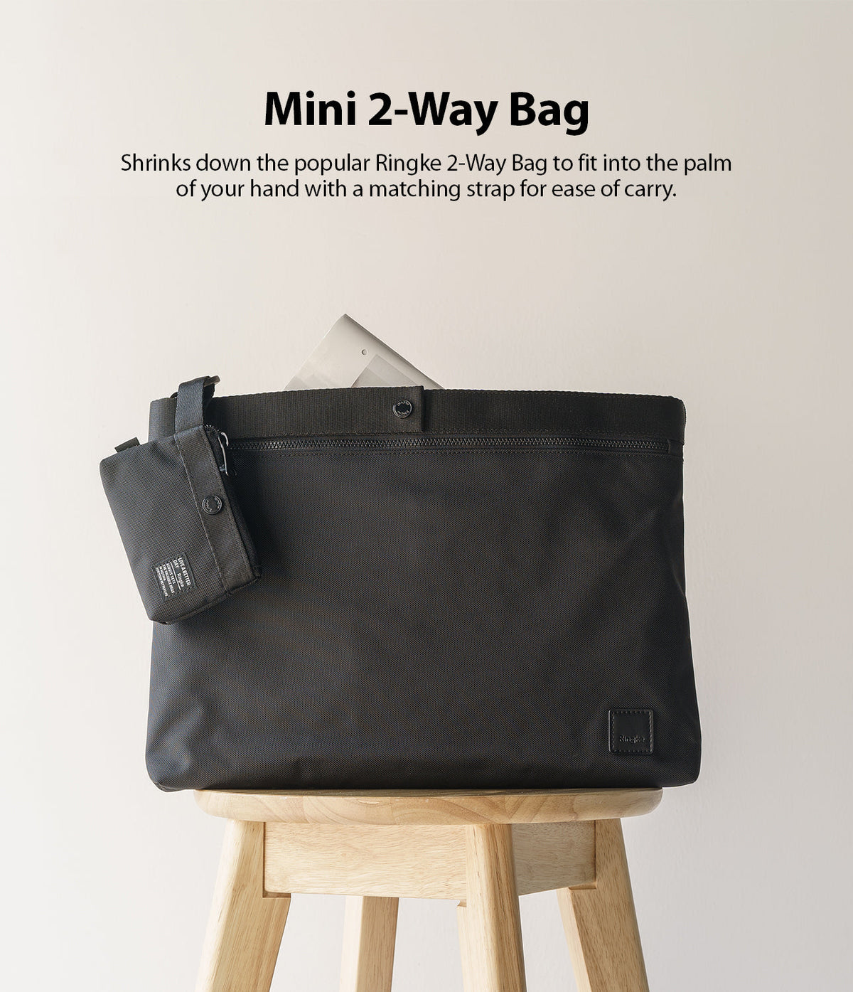 Mini Pouch | 2-Way Bag Miniature - A small black pouch attached to a larger black bag sitting on a wooden stool.