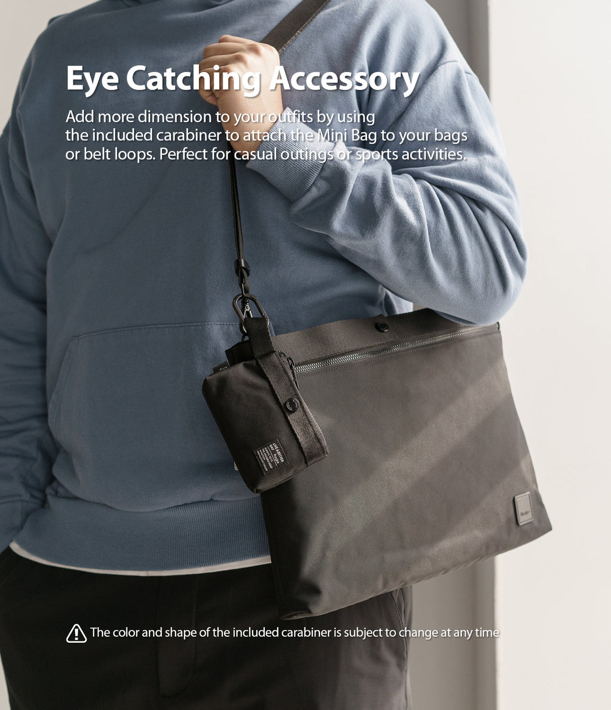 Mini Pouch | 2-Way Bag Miniature - A black mini pouch attached by a carabiner to a larger black shoulder bag worn by a person.