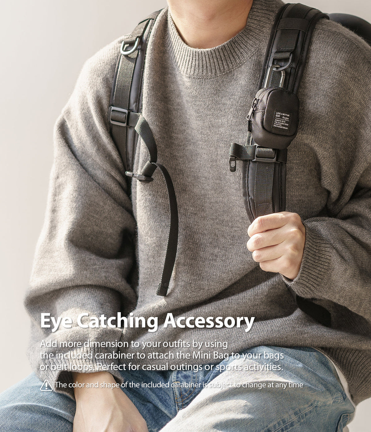 Mini Pouch | Block - A small black pouch attached to a backpack strap with a carabiner, worn by a person in a grey sweater.