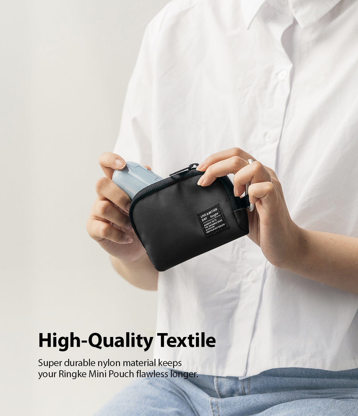 Mini Pouch | Half-Pocket - Hands holding a black nylon mini pouch with a small branded label, partially open to reveal a blue case.