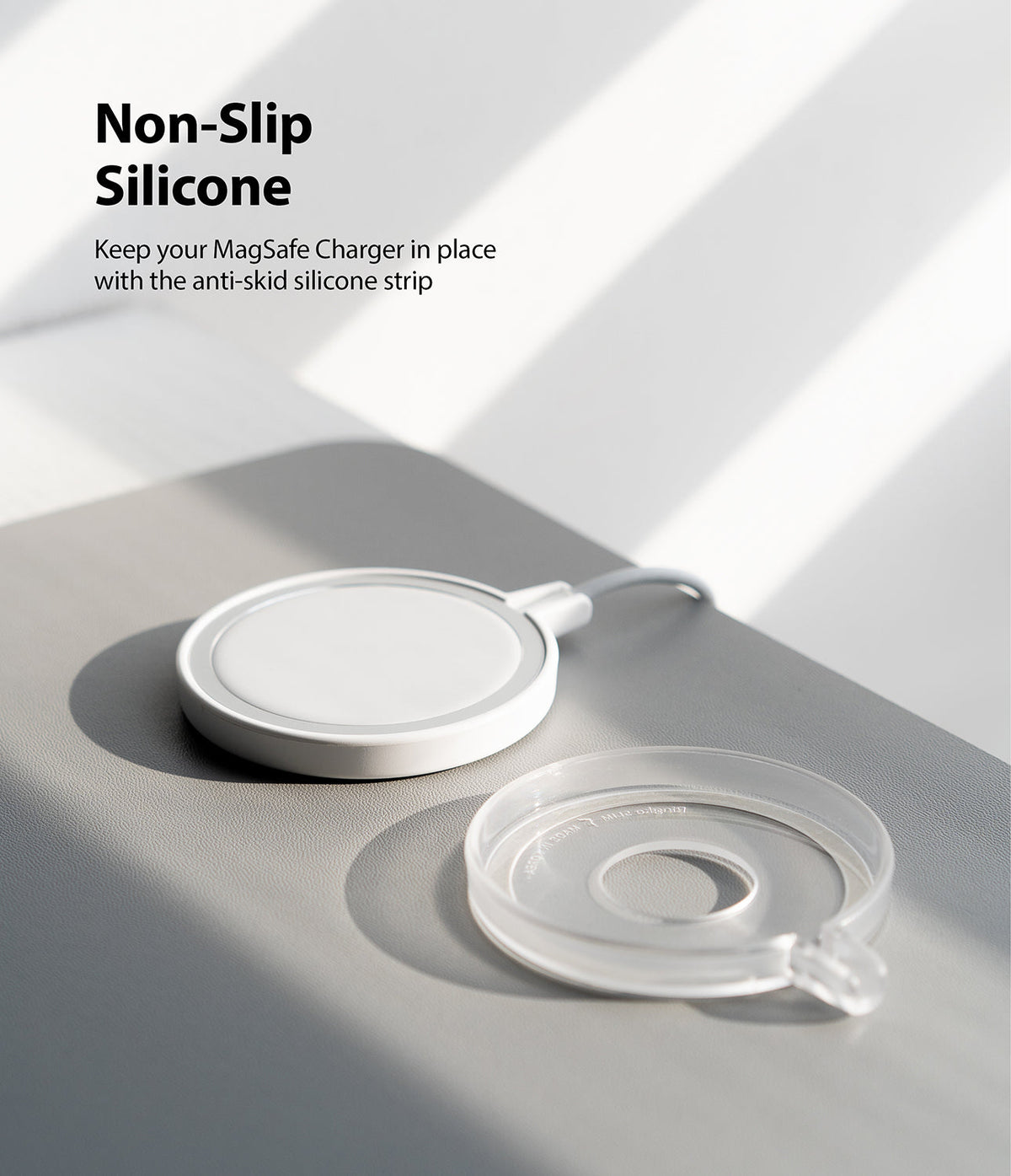 MagSafe Charger Case | Slim - A white MagSafe charger next to a clear, circular silicone anti-slip case on a gray surface.