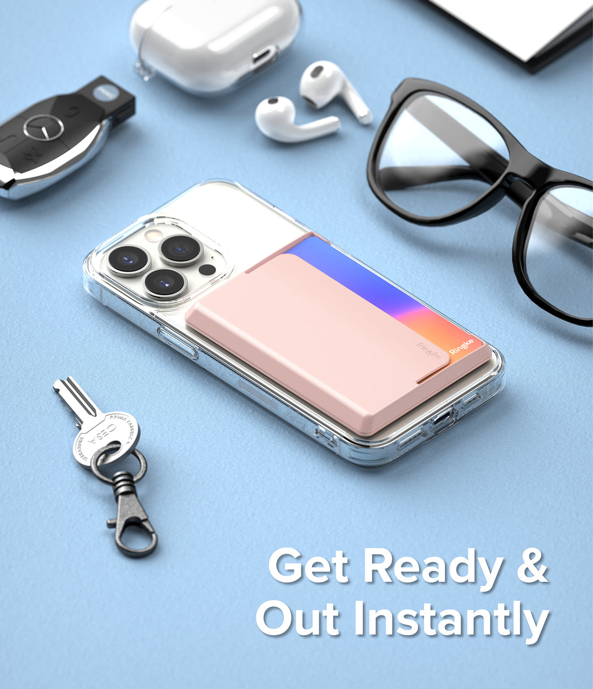 Card Holder | Magnetic Side Slot - Pink magnetic card holder attached to a clear phone case on a blue surface with accessories.