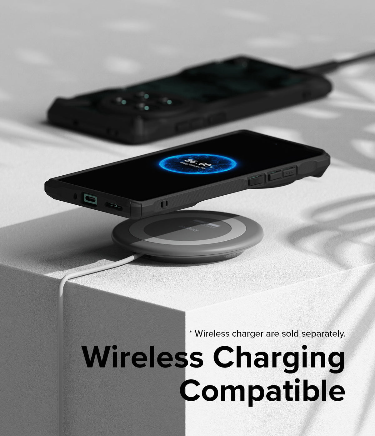 OnePlus 12 Case | Fusion-X - A black smartphone in a rugged case wirelessly charging on a grey pad atop a white block.