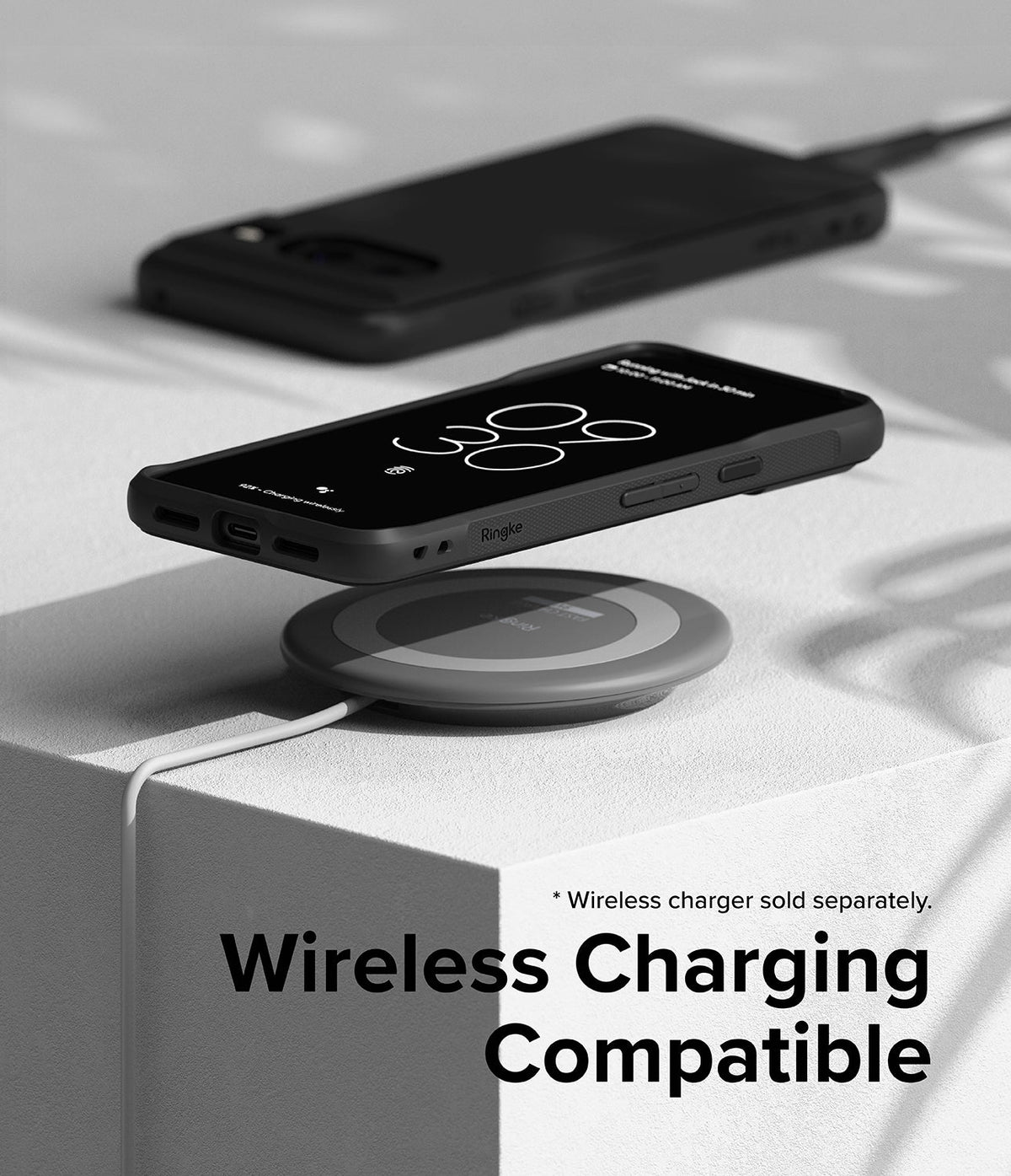 Google Pixel 8 Case | Onyx - A black phone case on a wireless charging pad with a second phone in the background.