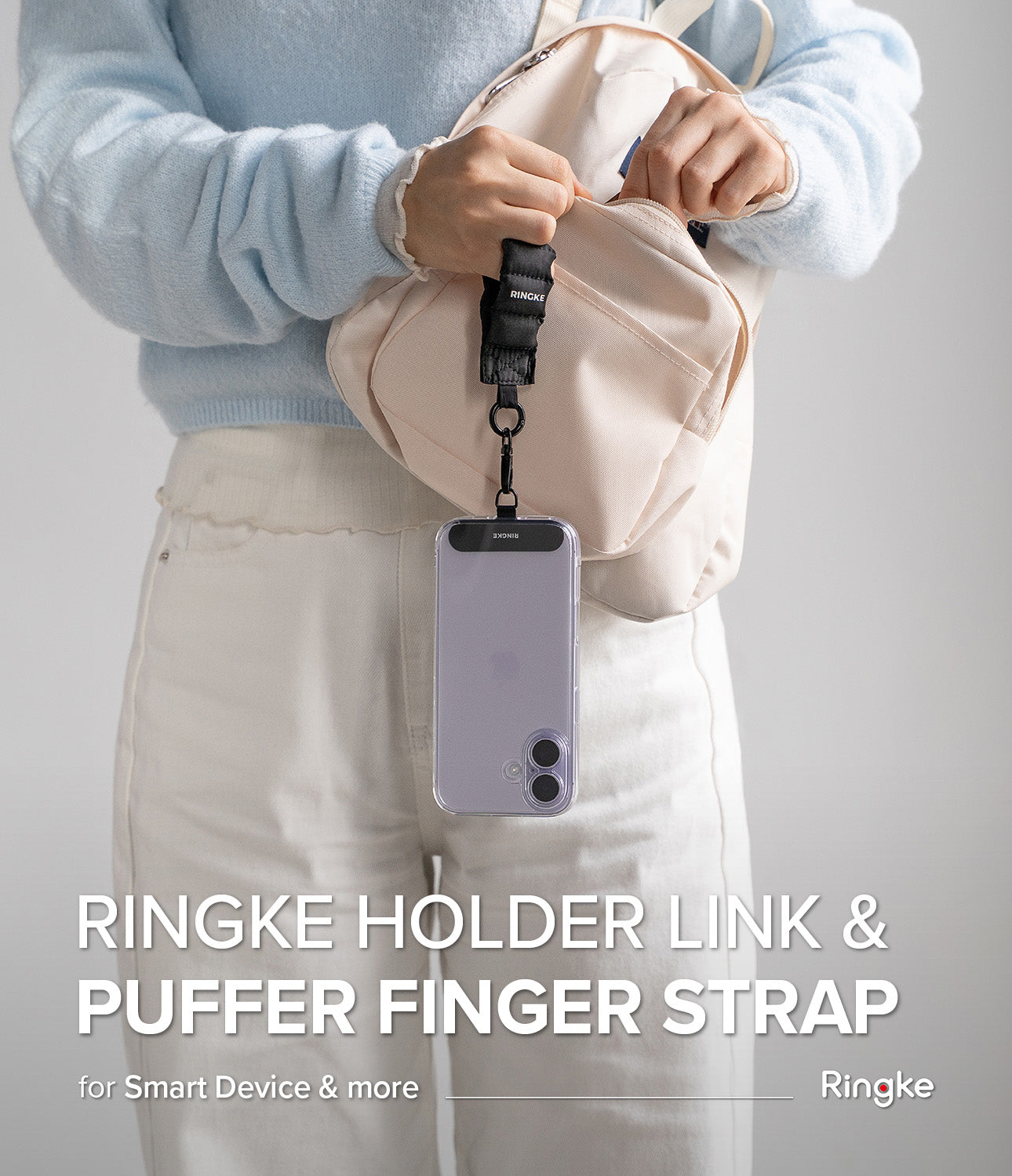 Holder Link Puffer | Finger - A black puffer finger strap attached to a smartphone case hanging from a person's hand.