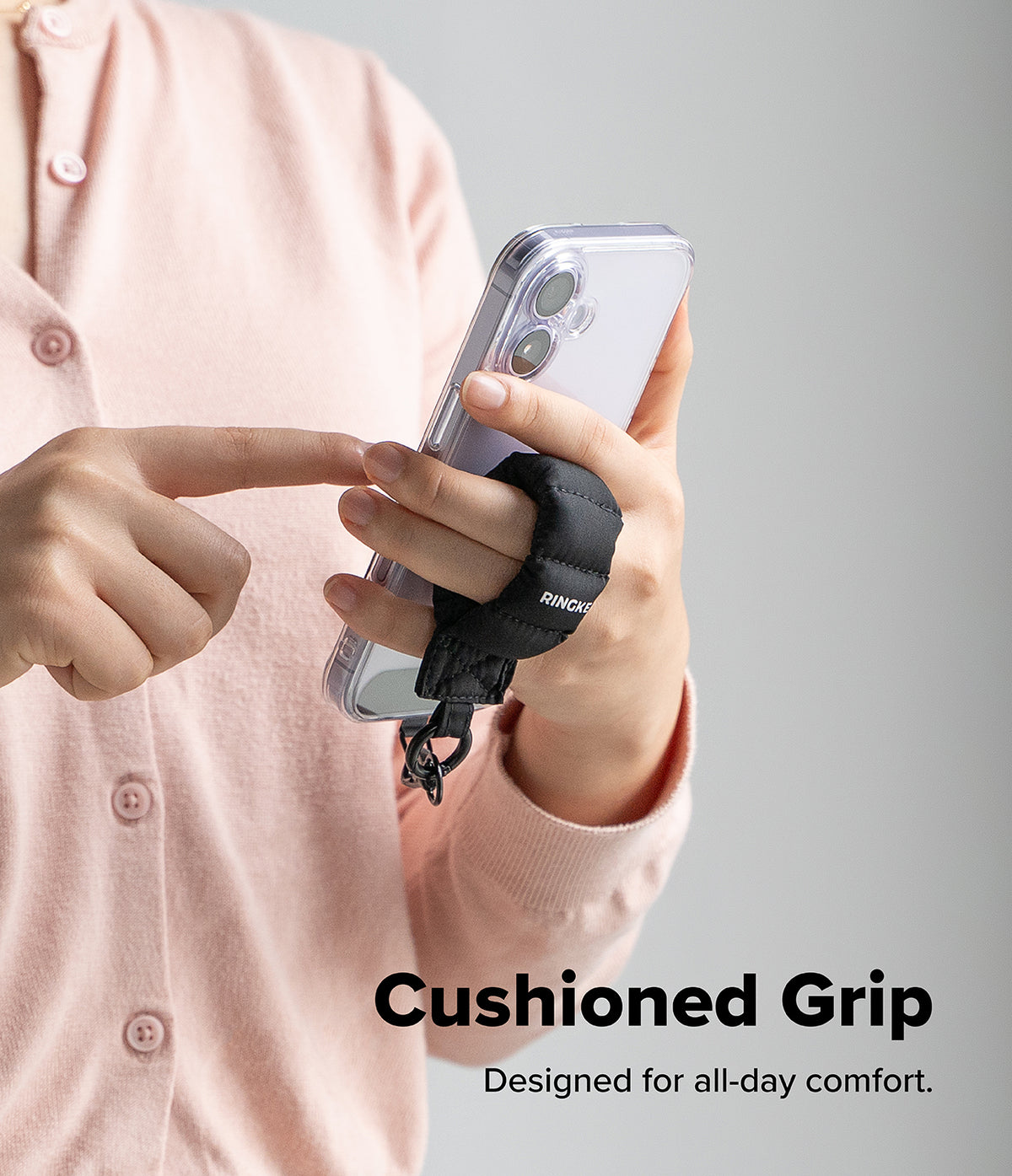 Holder Link Puffer | Finger - A person holds a smartphone with a black, quilted, cushioned finger strap attached.