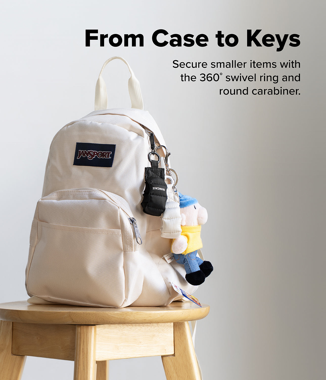 Holder Link Puffer | Finger - A cream JanSport backpack on a wooden stool with black and white puffer finger straps attached.