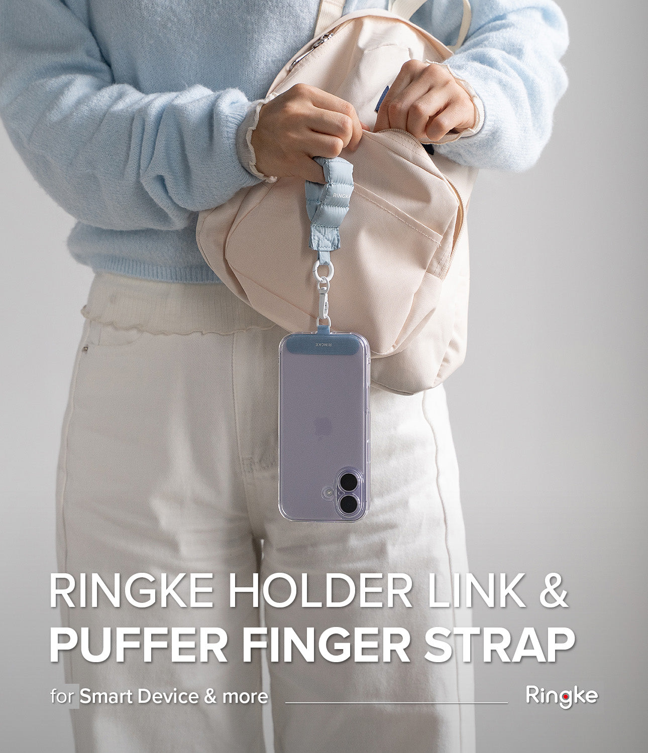 Holder Link Puffer | Finger - A person holds a light blue puffer finger strap attached to a phone case hanging from their hand.
