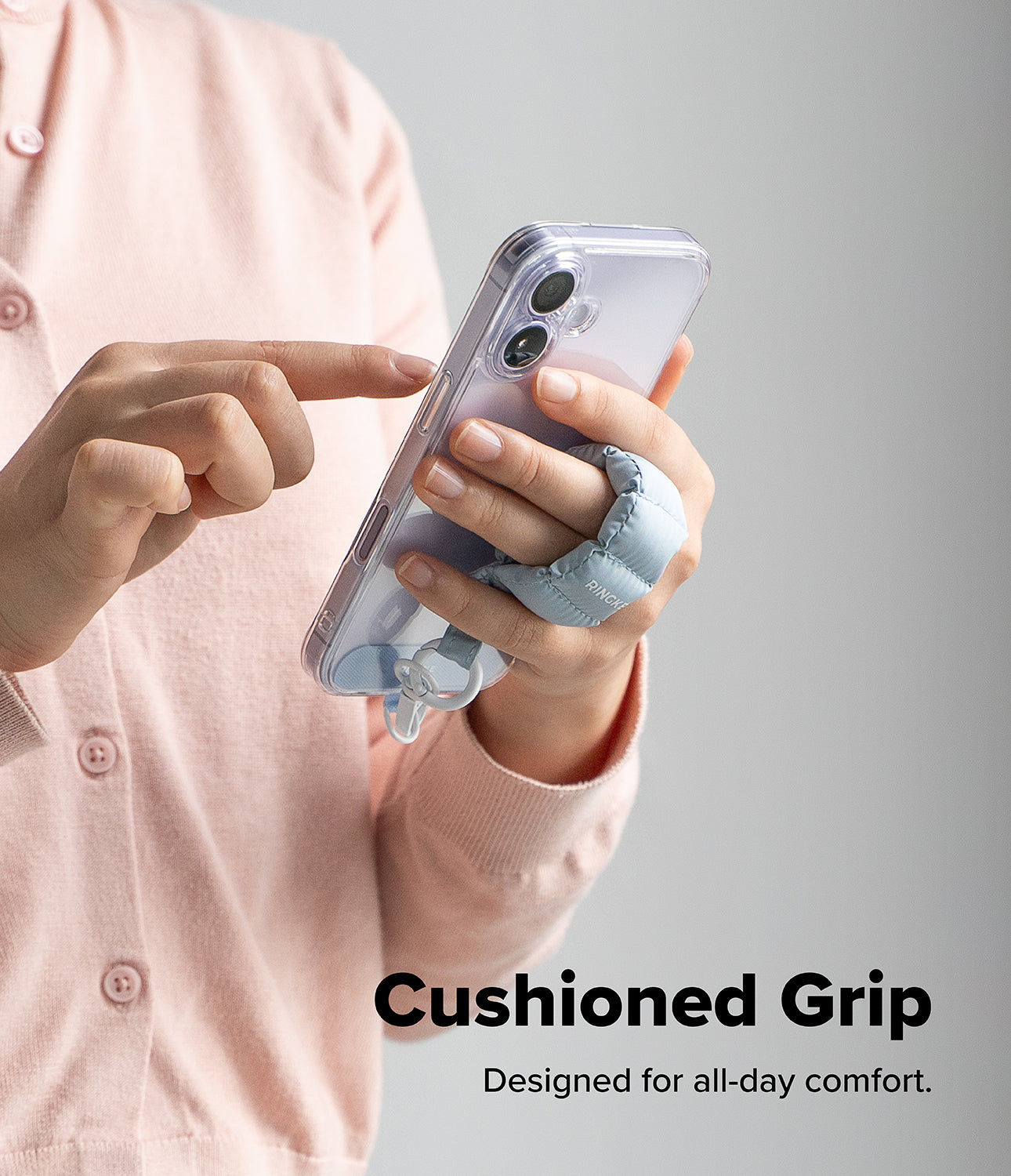 Holder Link Puffer | Finger - A person holding a phone with a light blue, quilted, cushioned finger strap for a secure grip.