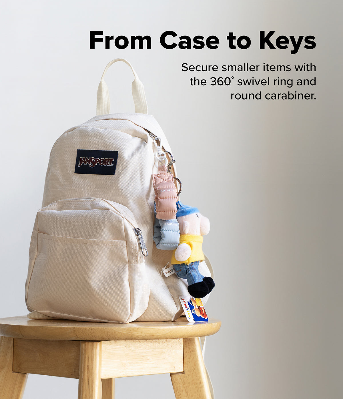 Holder Link Puffer | Finger - Cream backpack on a wooden stool with puffer finger straps and a plush toy attached.