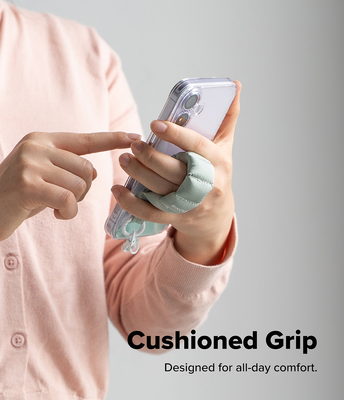 Holder Link Puffer | Finger - A person holds a smartphone with a sage green, quilted puffer-style finger strap for a secure grip.