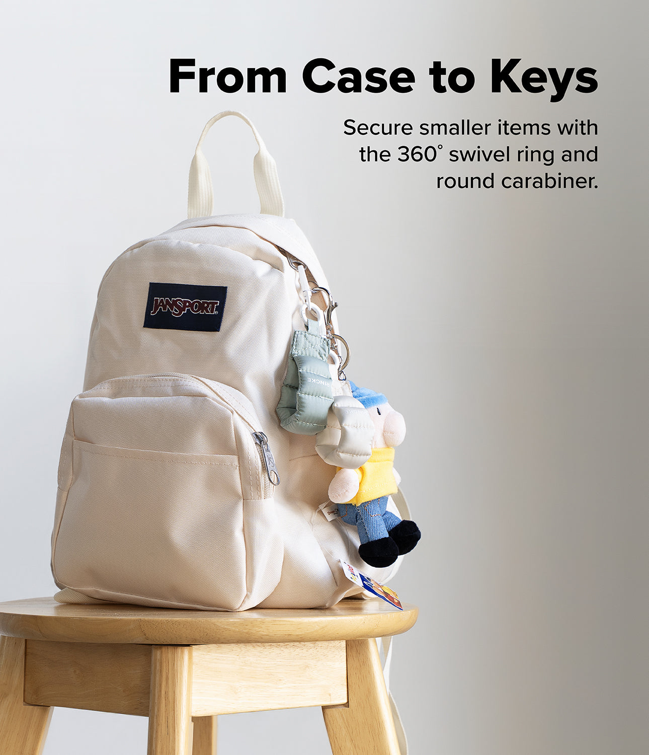 Holder Link Puffer | Finger - A cream Jansport backpack on a wooden stool with a puffer finger strap and plush toy attached.