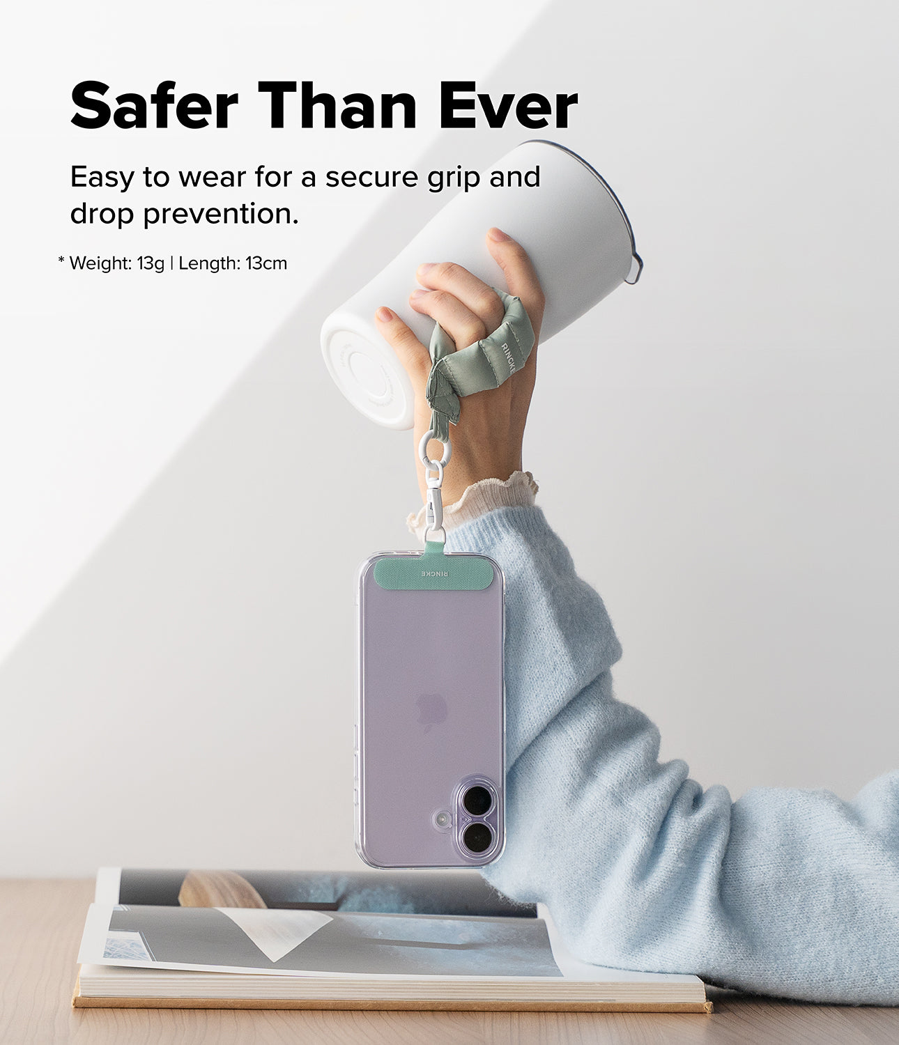 Holder Link Puffer | Finger - A hand holds a white tumbler with a sage green puffer finger strap attached to a phone.