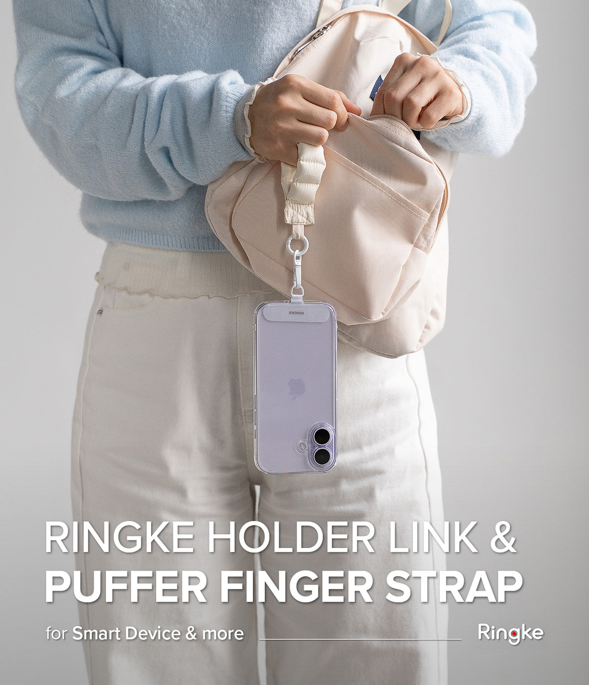 Holder Link Puffer | Finger - A person holds a beige puffer finger strap attached to a light purple smartphone case.