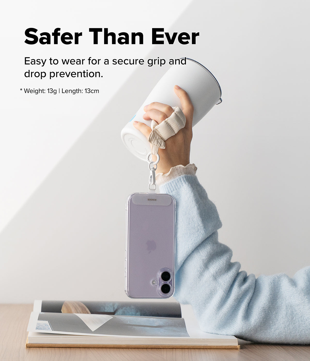 Holder Link Puffer | Finger - A hand holding a tumbler with a beige puffer finger strap attached to a smartphone case.