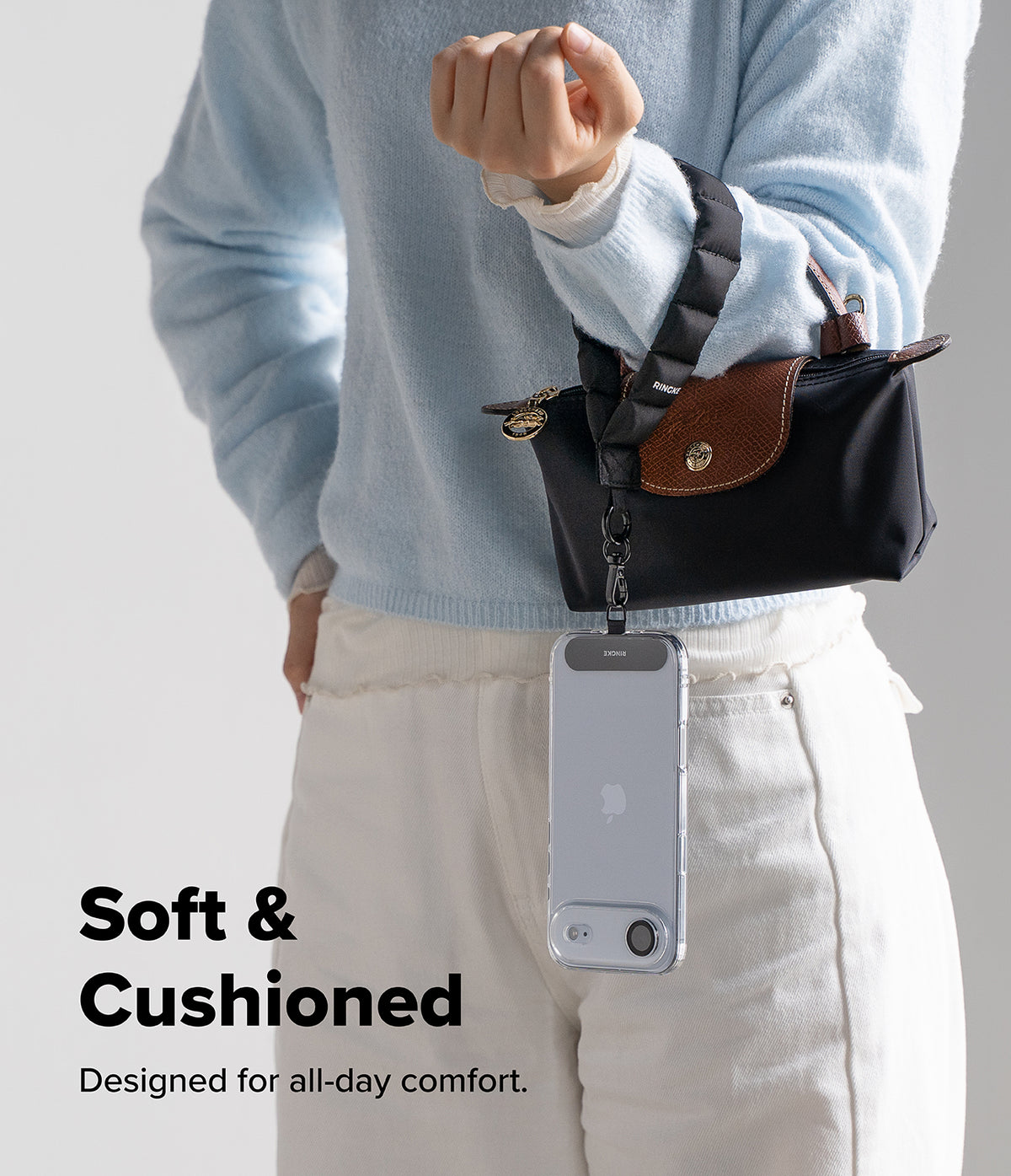 Holder Link Puffer | Hand - A person wearing a black puffer wrist strap attached to a small handbag and a clear phone case.