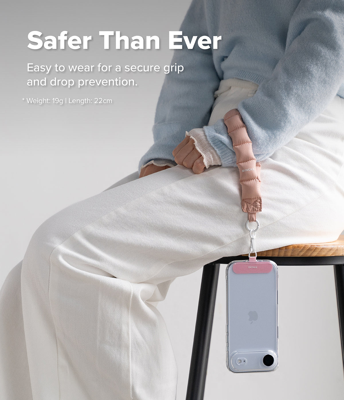 Holder Link Puffer | Hand - A person wearing a pink puffer wrist strap attached to a smartphone hanging from their hand.