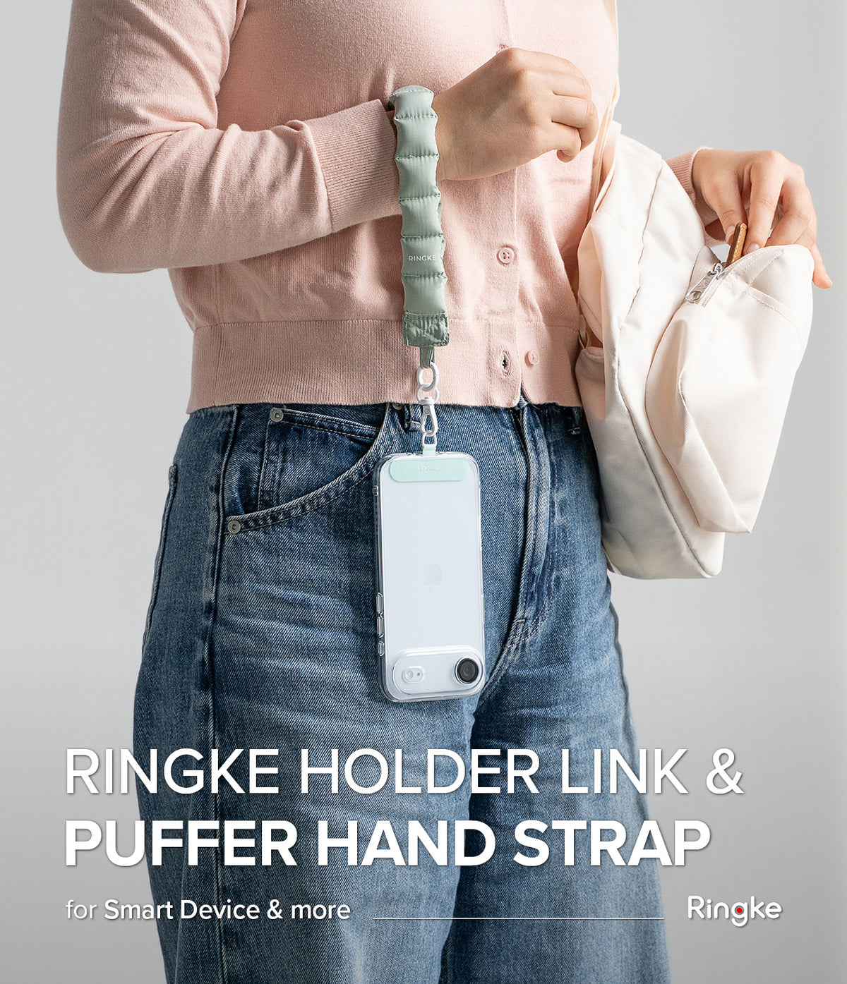 Holder Link Puffer | Hand - A person wearing a sage green quilted puffer hand strap attached to a clear smartphone case.