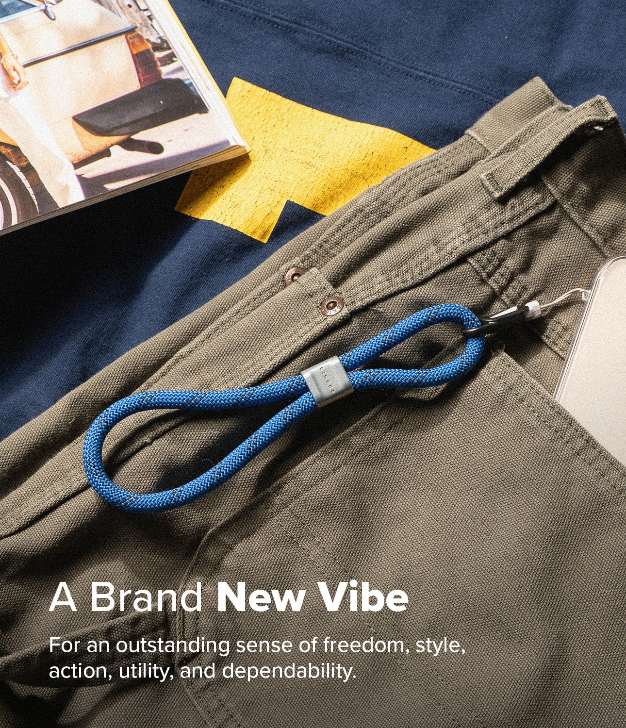 Rope Hand Strap - Blue rope wrist strap with a grey metal clasp attached to a phone, resting on olive pants and a shirt.