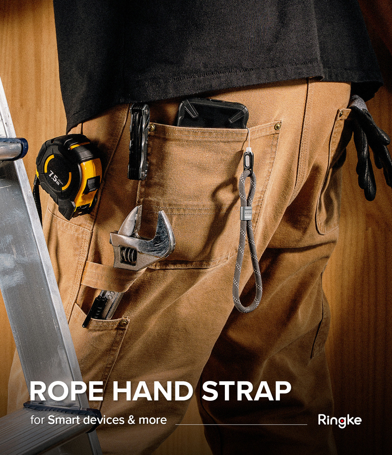 Rope Hand Strap - Gray rope wrist strap attached to a phone in a worker's pocket, surrounded by tools on brown work pants.