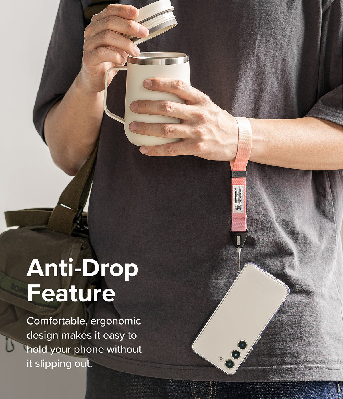 Hand Strap | Basic - A person wearing a pink fabric wrist strap attached to a smartphone, holding a mug with their other hand.