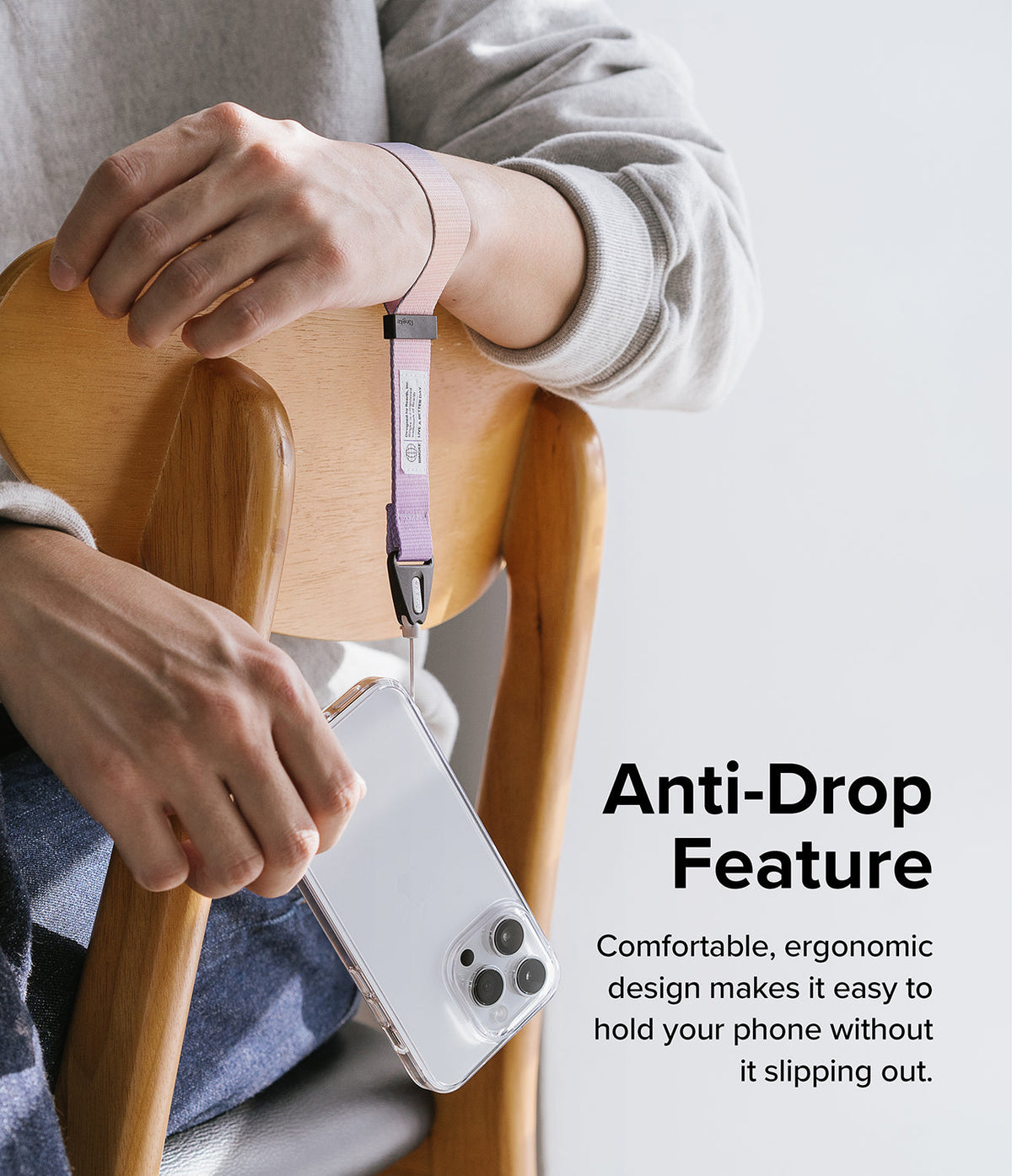 Hand Strap | Basic - A person wears a two-tone pink and purple fabric wrist strap attached to a clear smartphone case.