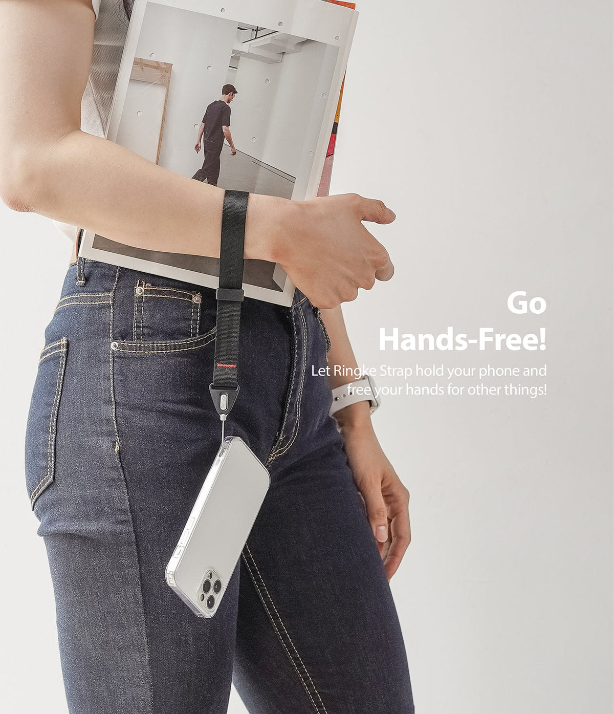 Hand Strap | Black / Neon Orange - A person wearing a black wrist strap attached to a smartphone, holding a magazine.