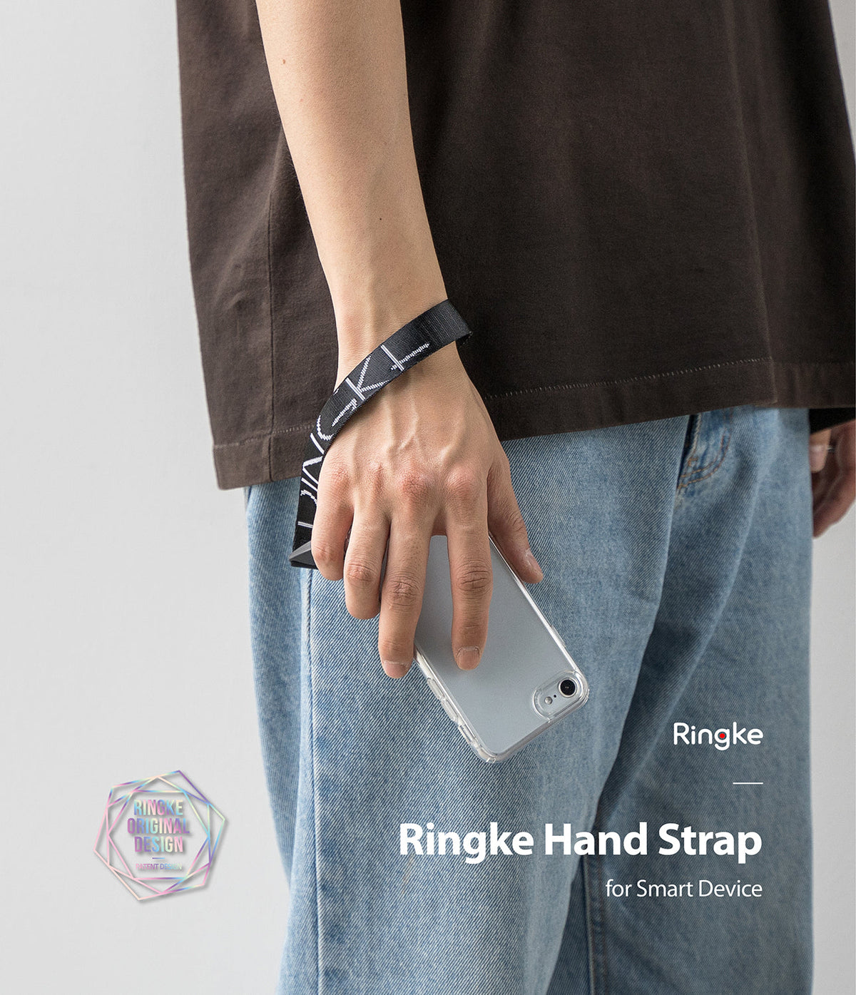 Hand Strap | Lettering - A person wearing a black wrist strap with white Ringke lettering while holding a clear phone case.