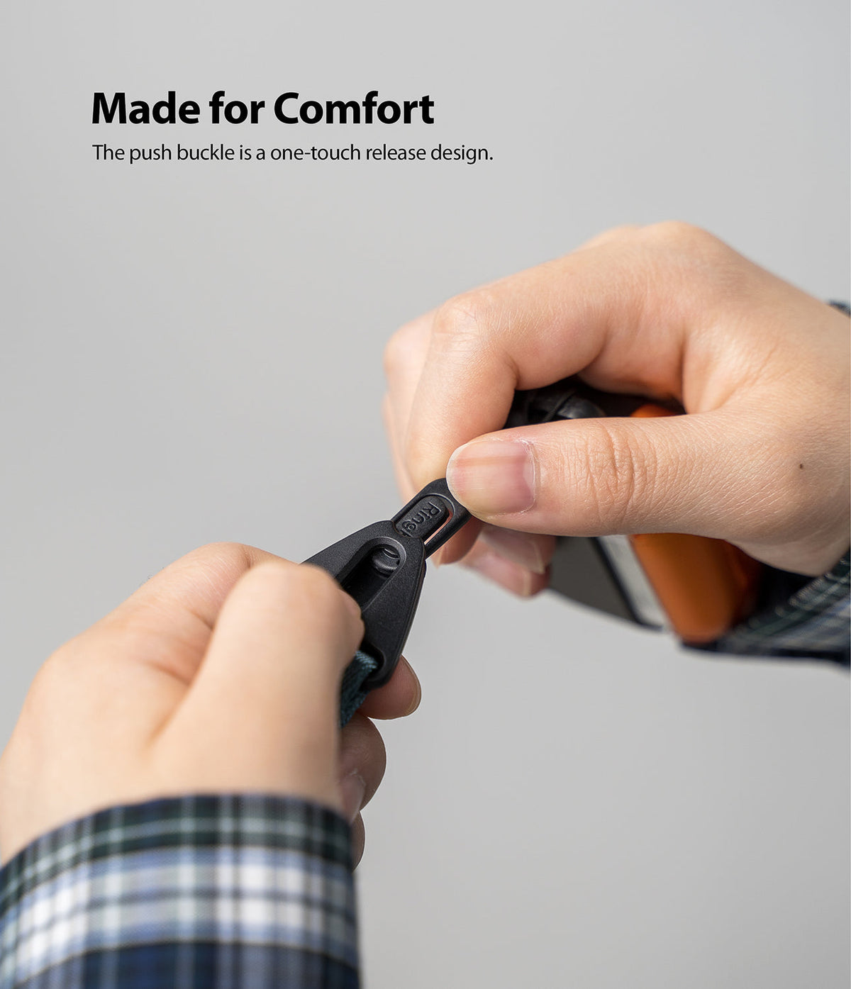 Hand Strap | Lettering - Hands pressing the push buckle on a black strap with Ringke branding embossed on the connector.