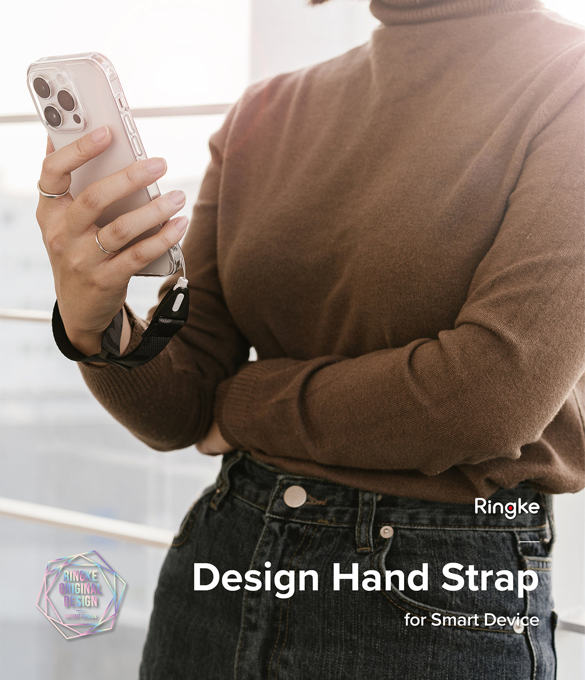 Hand Strap | Basic - Person wearing a brown sweater holding a smartphone secured by a black fabric hand strap.
