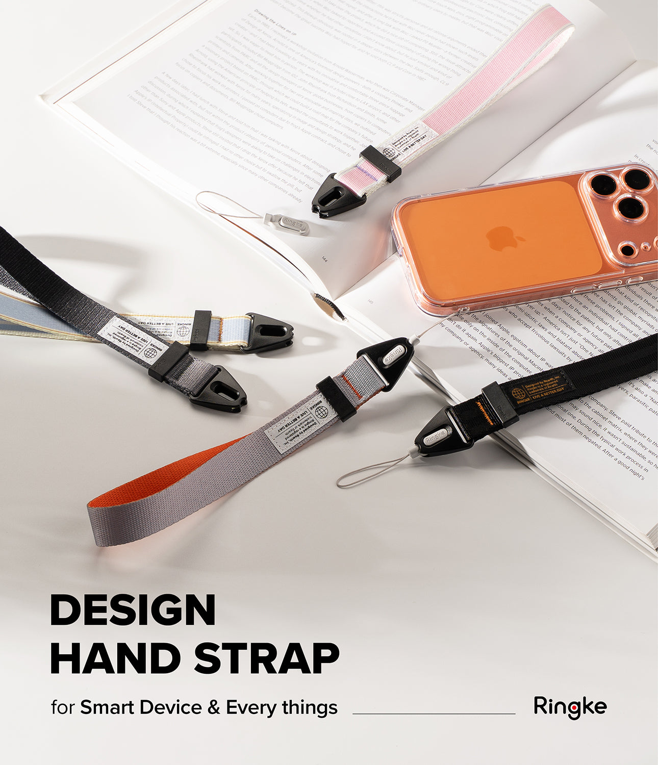 Design Hand Strap - Four colorful fabric wrist straps with black plastic connectors arranged on an open book near a phone.