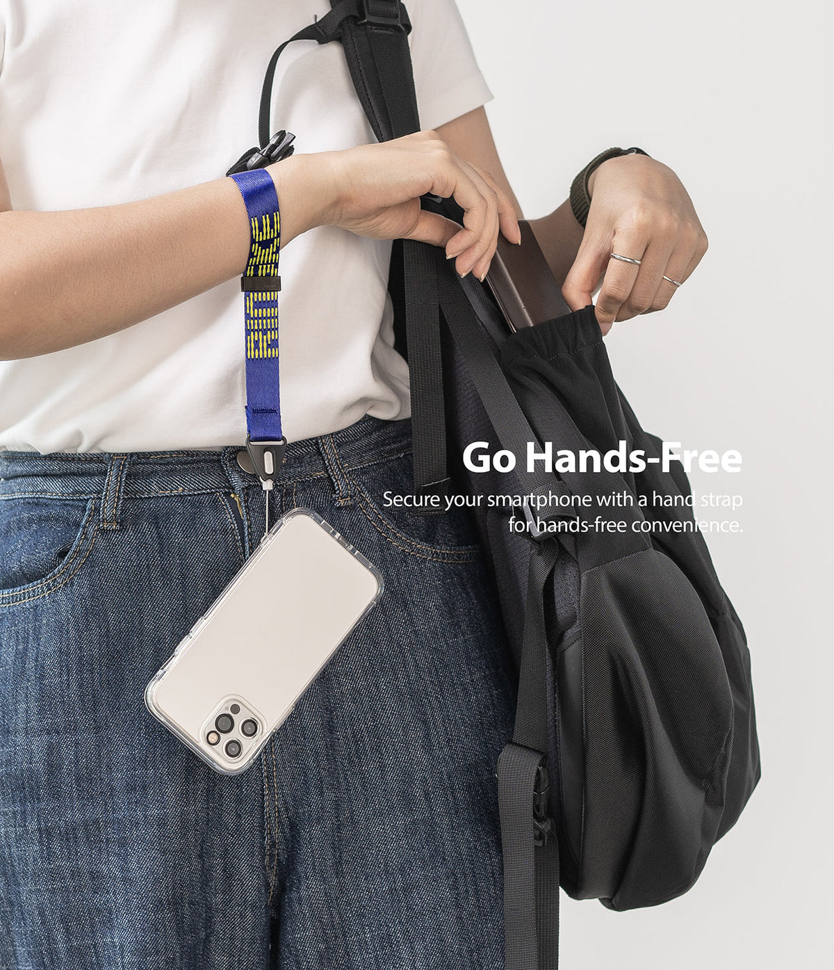 Hand Strap | Lettering - A person wearing a blue patterned wrist strap attached to a smartphone hanging by their side.