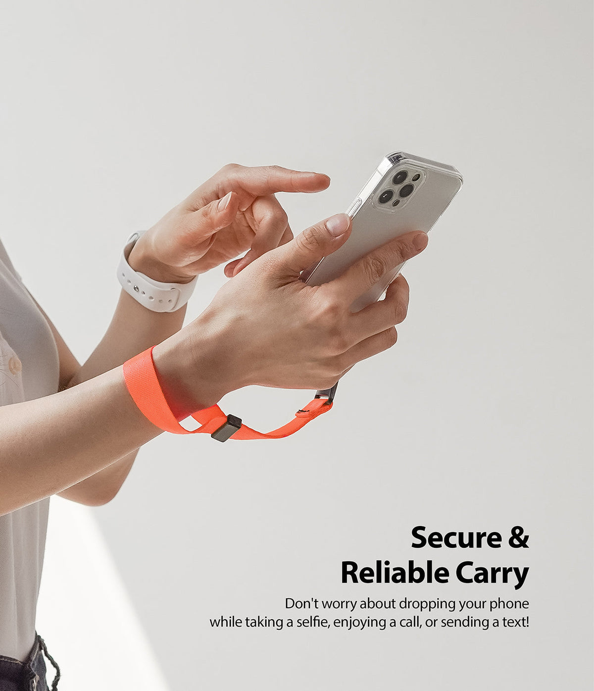 Hand Strap | Black / Neon Orange - A neon orange wrist strap attached to a smartphone held by a person.