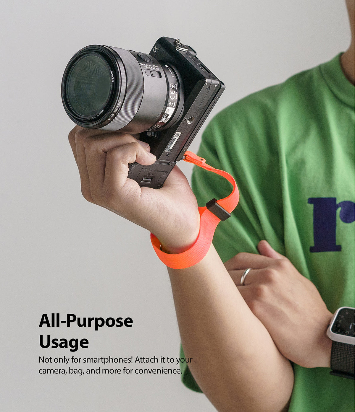 Hand Strap | Black / Neon Orange - A person wearing a neon orange wrist strap attached to a black mirrorless camera.