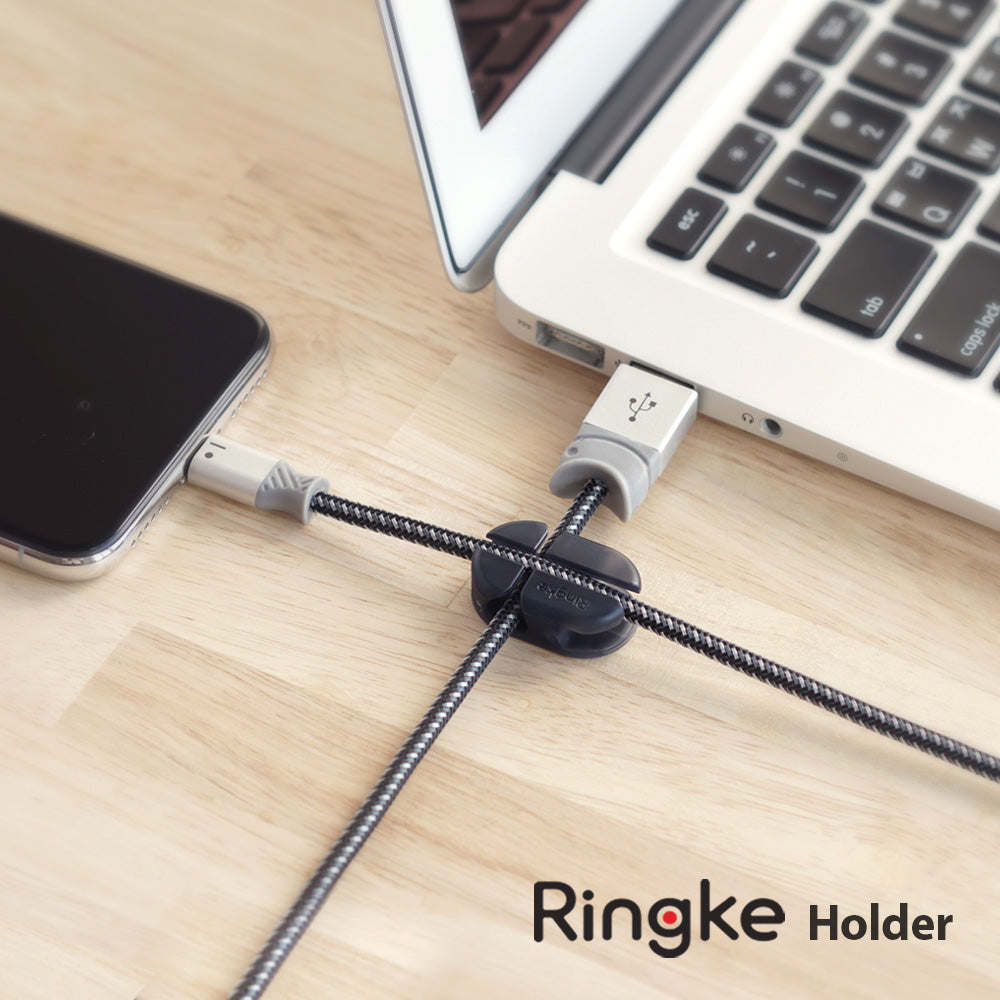 Cable Holder - A black cable organizer securing a braided charging cable connected to a smartphone and a laptop.