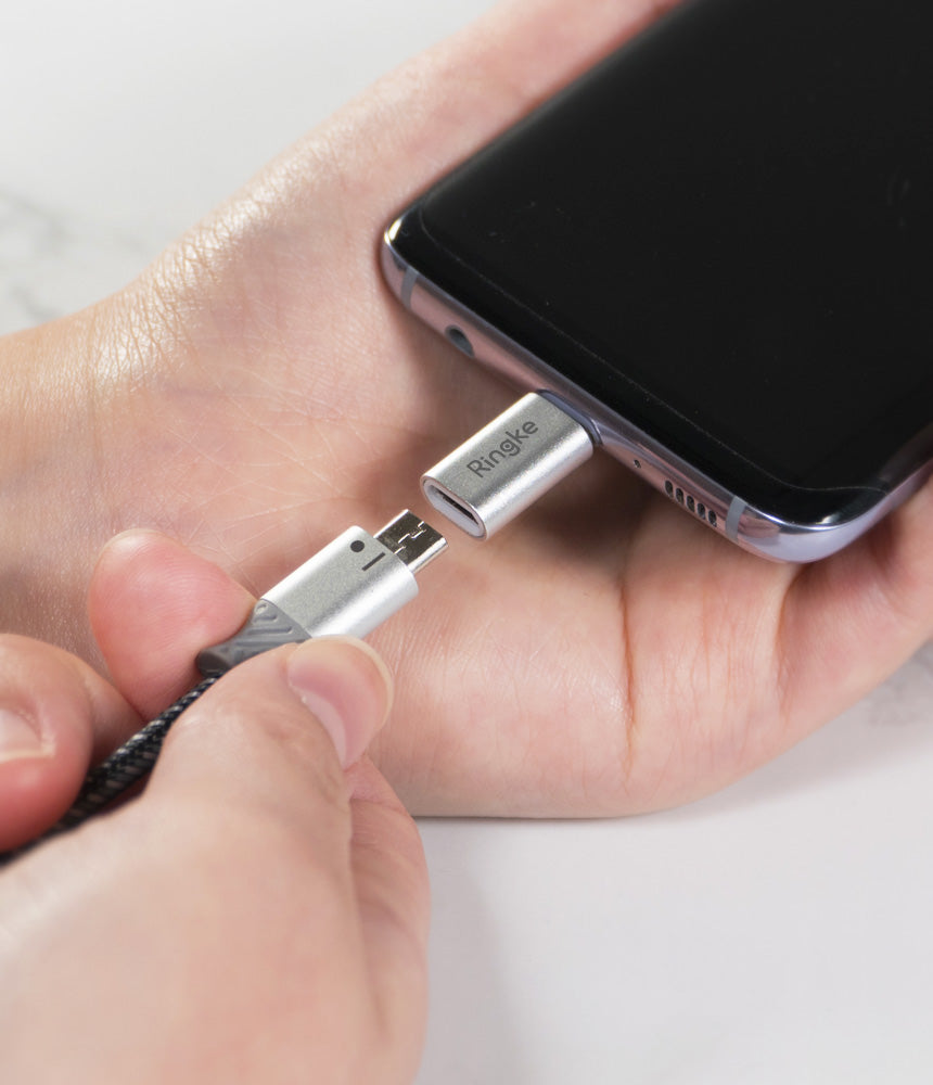 Micro USB to Type C Adapter - A hand holding a Micro USB cable about to plug into a silver Ringke USB-C adapter on a phone.