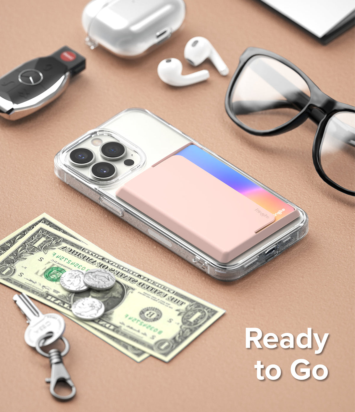 Card Holder | Side Slot - Pink card holder attached to a clear phone case, surrounded by personal items on a tan surface.