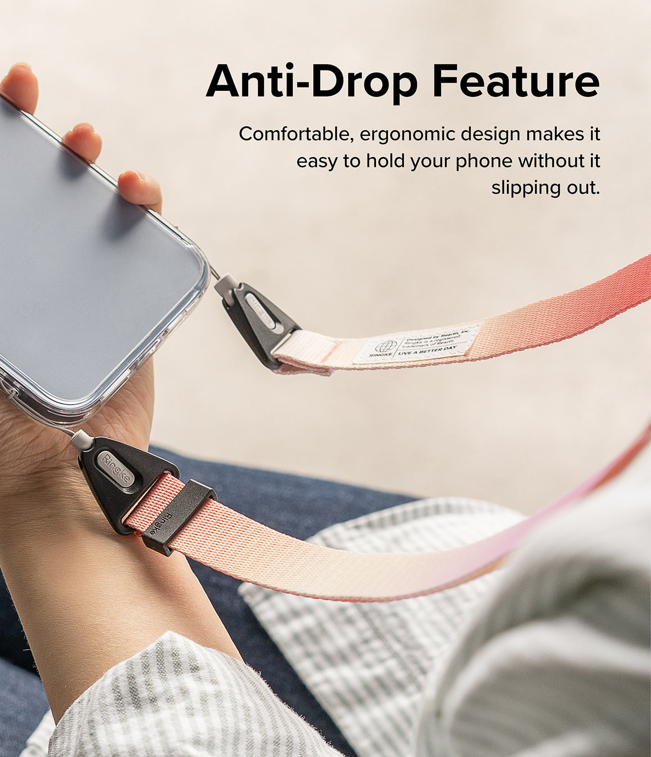Design Shoulder Strap - A hand holding a phone attached to a pink and orange gradient fabric strap with black hardware.