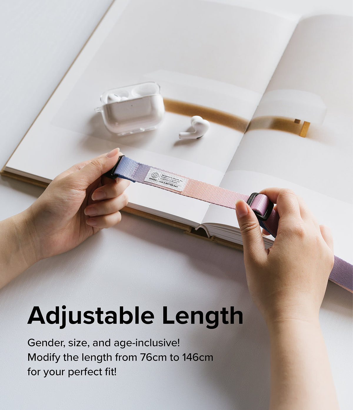 Design Shoulder Strap - Hands adjusting a two-tone pink and purple fabric strap with a branded label over an open book.
