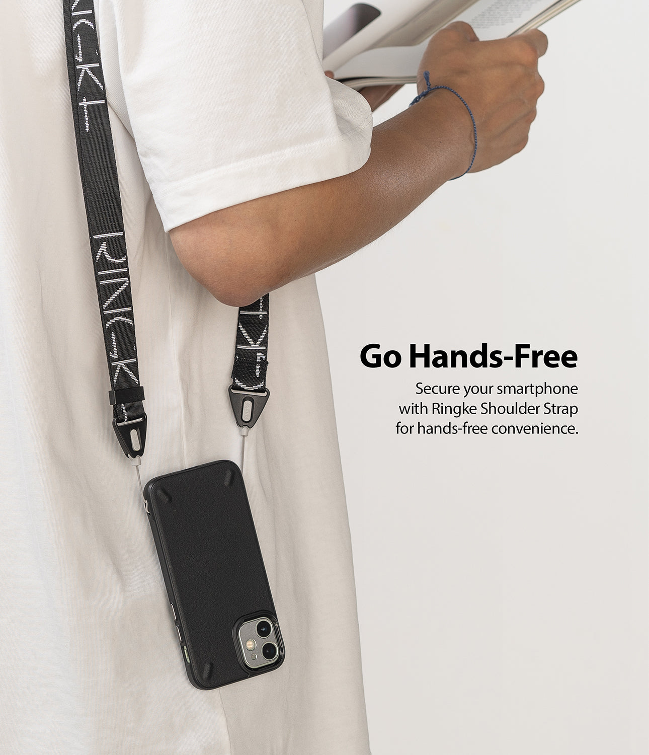 Design Shoulder Strap - Person wearing a black branded phone strap attached to a smartphone case over a white t-shirt.