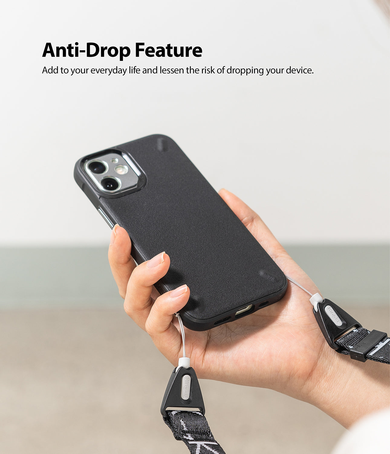Design Shoulder Strap - Hand holding a black phone case attached to a branded black and white shoulder strap.