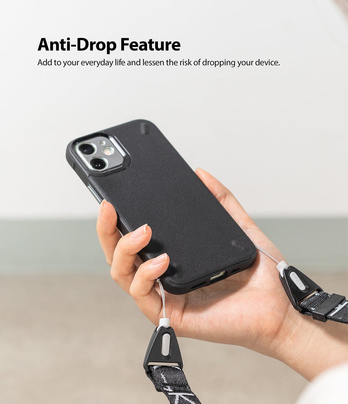 Shoulder Strap | Lettering - Hand holding a black phone case attached to a branded black shoulder strap with white lettering.