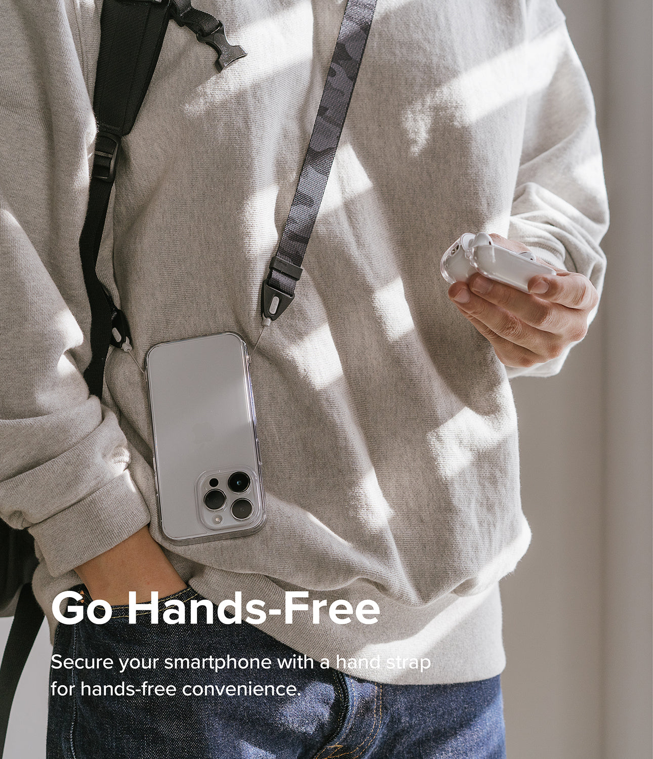 Design Shoulder Strap - Person wearing a smartphone on a camouflage shoulder strap while holding wireless earbuds.
