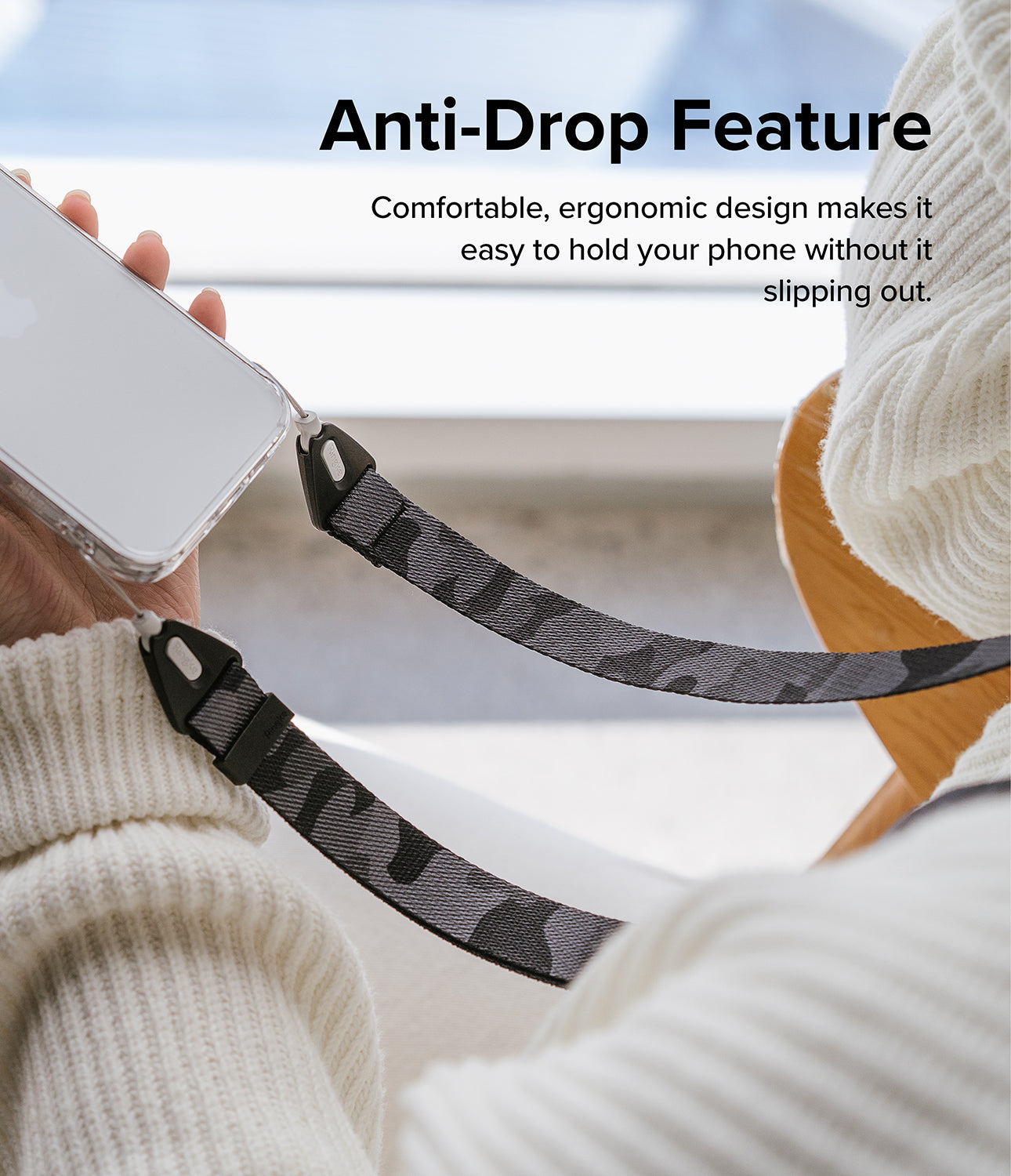Design Shoulder Strap - A person in a white sweater holds a phone attached to a grey camouflage patterned shoulder strap.