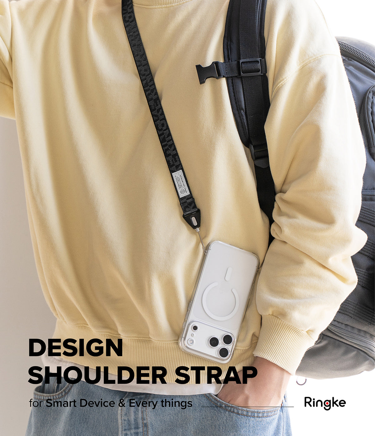 Design Shoulder Strap - Person wearing a black branded shoulder strap attached to a clear smartphone case over a yellow sweater.