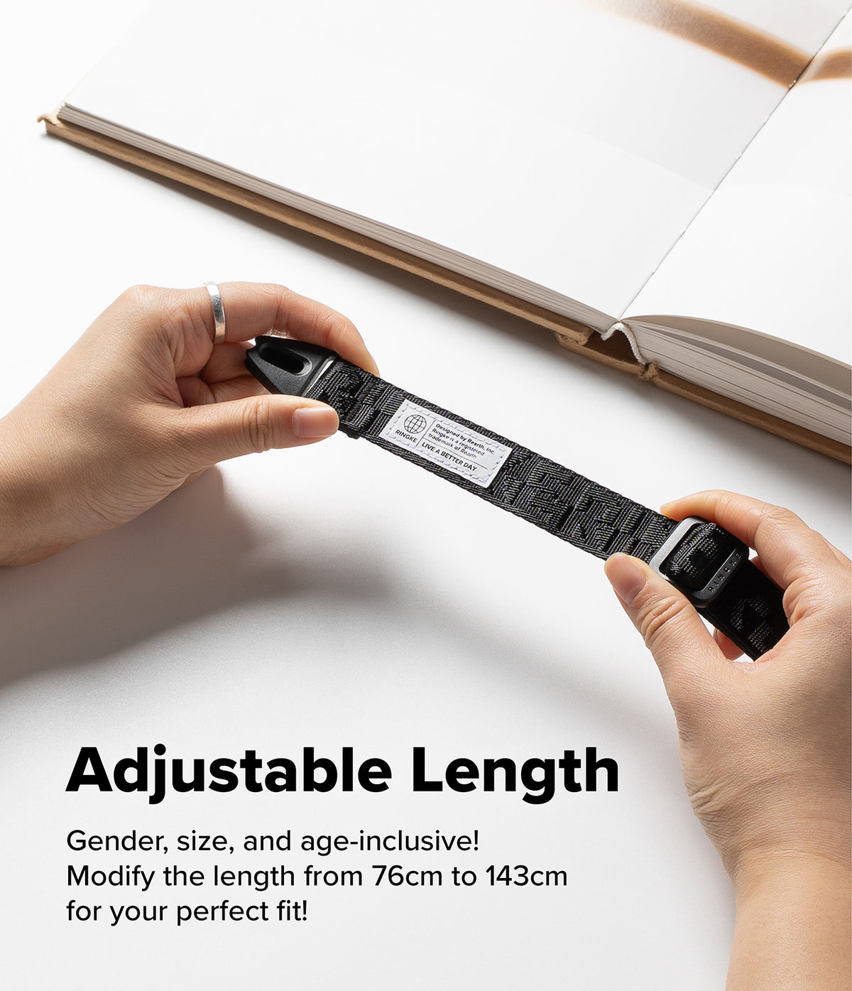 Design Shoulder Strap - Hands holding a black adjustable strap with a Ringke brand tag against a white background.