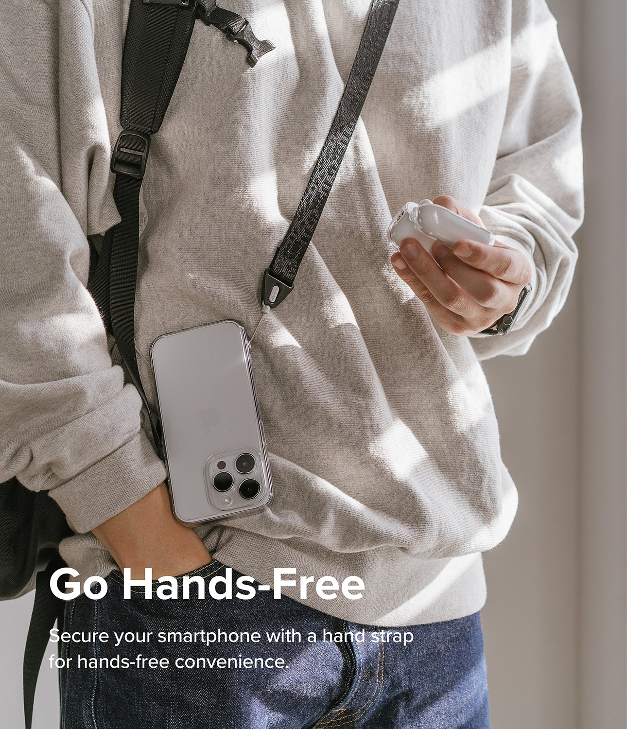Design Shoulder Strap - A person wearing a smartphone on a black patterned shoulder strap while holding wireless earbuds.